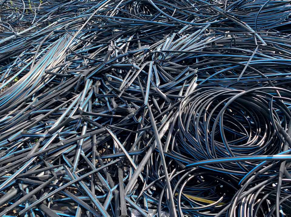 Ansammlung von schwarzen Schläuchen und Kabelummantelungen auf dem Recyclinghof, Kunststoff-Abfälle aus der Kabelproduktion zum recyceln